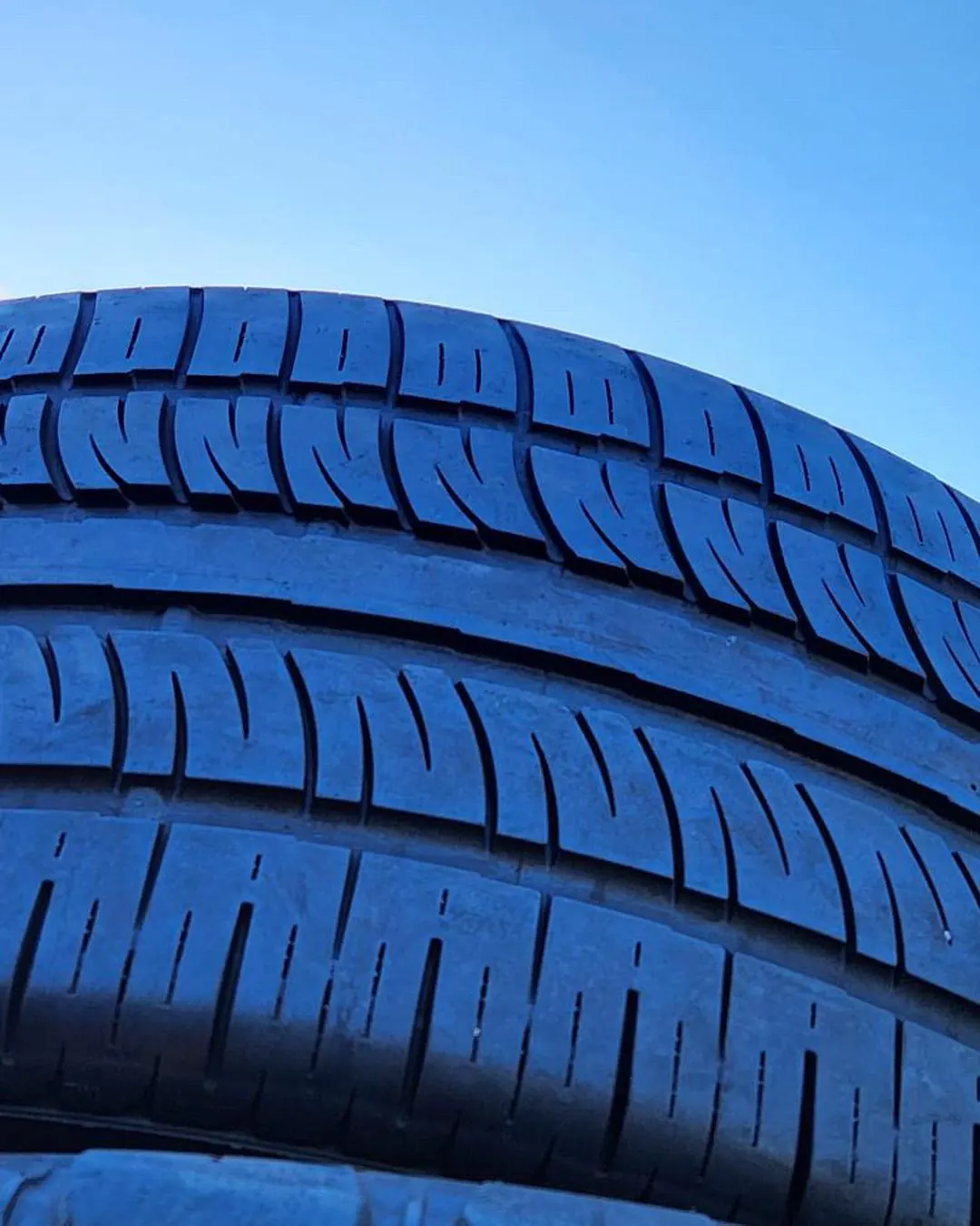 Tall stack of used tires in partial shade